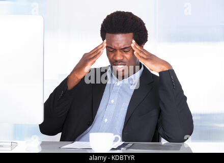 Ritratto di un imprenditore che soffrono di mal di testa in ufficio Foto Stock