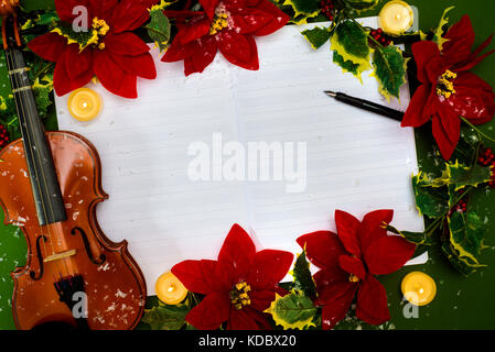 Il violino e la musica aperta manoscritto sullo sfondo verde. concetto di natale Foto Stock