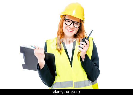 Una giovane donna caposquadra con gli occhiali e un casco giallo con un walkie-talkie isolato Foto Stock