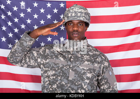 Ritratto di afro-americano soldato dell'esercito salutando davanti della bandiera americana Foto Stock