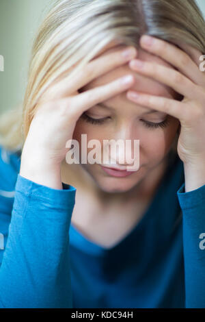 Giovane donna che soffre di depressione con testa in mani Foto Stock