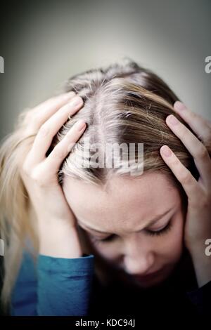 Giovane donna che soffre di depressione con testa in mani Foto Stock