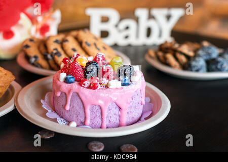 Torta di compleanno e muffin con il messaggio di saluto di legno segni su sfondo rustico in legno per cantare baby vacanza e dolci. Foto Stock