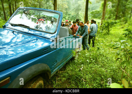 Persone che cercano di spingere il Broken auto a forest Foto Stock