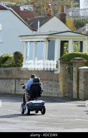 Un uomo a cavallo di un handicap uno scooter o in bicicletta lungo il lungomare o spianata sulla isola di Wight a Cowes. Foto Stock