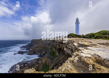 Cape Nelson lighthouse in piedi su un robusto promontorio sopra l'oceano sotto il cielo tempestoso. victoria, Australia. Foto Stock