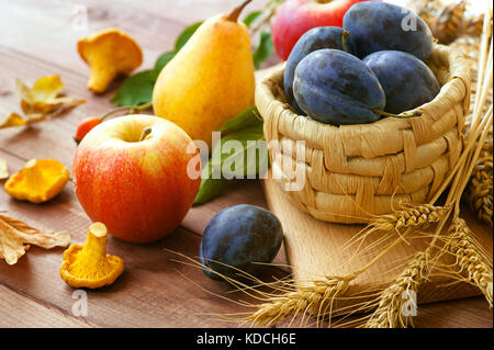 Fresche e mature pere, prugne e mele in un recipiente su sfondo naturale. messa a fuoco selettiva Foto Stock