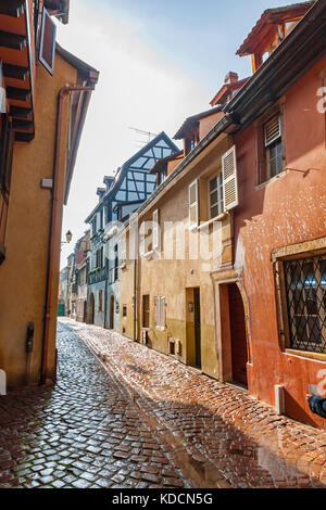 Strada stretta e tradizionali case a graticcio colorate nella città di Colmar (conosciuta anche come piccola Venezia), Alsazia, Francia. Vista soleggiata dopo la pioggia Foto Stock