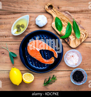 Materie filetto di salmone nella piastra nera con ingredienti olio di oliva , Sale Himalayano e erbe aromatiche basilico dolce ,finocchio ,salvia , Rosmarino , Aglio , Pepe e lem Foto Stock