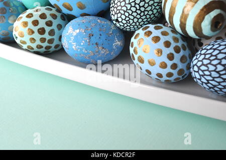 Decorate le uova di pasqua con oro a pois su mint teal aqua sfondo blu. Stile immagine stock con copia spazio. La pasqua e la molla del tema. Foto Stock