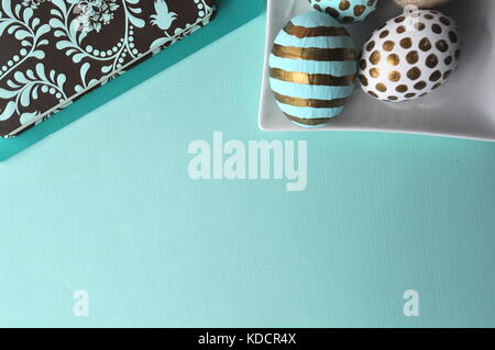 Decorate in oro le uova di pasqua con pois e strisce su teal aqua mint sfondo blu. Stile immagine stock con copia spazio. La pasqua e la molla del tema. Foto Stock