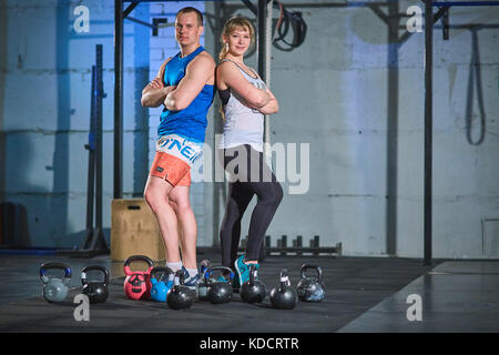 Uomo sportivo e giovane donna muscolare facendo un esercizio con pesi nella palestra Foto Stock