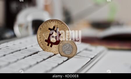 Valuta digitale metallo fisico bitcoin moneta sulla tastiera bianco vicino a sfera di vetro. Foto Stock