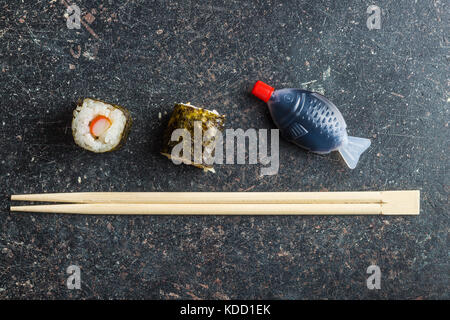 I sushi giapponesi Le bobine, bacchette e salsa di pesce sul vecchio tavolo da cucina. vista dall'alto. Foto Stock