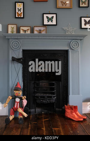 Vittoriano era accogliente e bizzarro camino circondato da parete blu, con fantoccio e bizzarro orange stivaletti e butterfly foto. Foto Stock