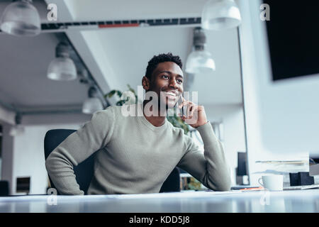 Ritratto di maschio rendendo esecutivo chiamata mentre è seduto in ufficio. Giovane imprenditore parlando al telefono cellulare. Foto Stock