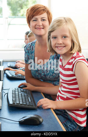 Ritratto di femmina pupilla elementare in classe computer con insegnante Foto Stock