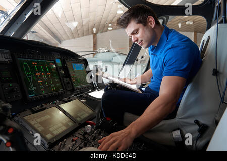 Maschio ingegnere aero con appunti lavora nel cockpit in elicottero Foto Stock