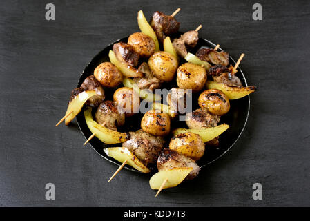 Pollo alla griglia del fegato e spiedini di verdure sulla piastra su sfondo nero Foto Stock
