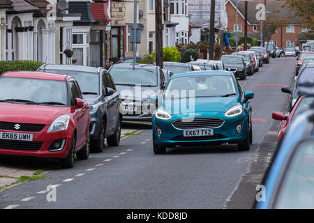 2017 Ford Fiesta modello Guida su strada stretta con altre auto parcheggiate su entrambi i lati Foto Stock