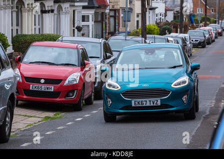 2017 Ford Fiesta modello Guida su strada stretta con altre auto parcheggiate su entrambi i lati Foto Stock