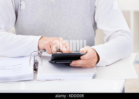 Close-up di uomo seduto a casa azienda calcolatrice e fatture Foto Stock