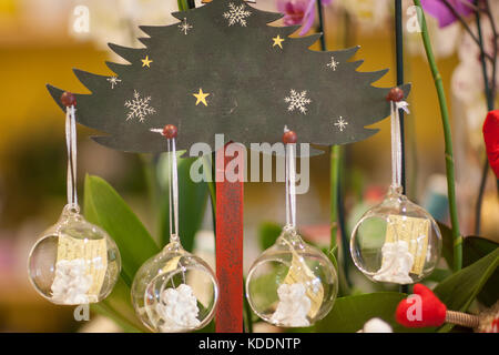 Appendere le decorazioni di Natale con angeli sulla fir artificiale su uno sfondo sfocato Foto Stock