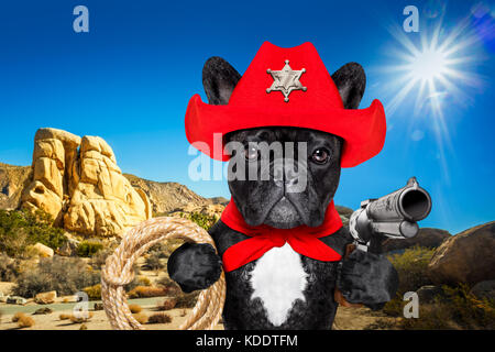 Western cowboy sheriff bulldog francese cane con corda , sciarpa rossa e pistola fuori nel deserto, indossando american Red Hat Foto Stock