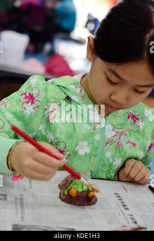 Enshi, Cina. 13 ottobre 2017. Gli studenti imparano a fare maschere dell'Opera Nuo a Enshi Tujia e nella prefettura autonoma di Miao nella provincia di Hubei della Cina centrale. Le maschere sono una caratteristica distintiva dell'Opera Nuo, un antico dramma popolare che è ancora popolare in molte province cinesi lungo il fiume Yangtze. Si ritiene che gli artisti della Nuo Opera acquisiscano la capacità di comunicare con le divinità una volta indossate le loro maschere. Crediti: ZUMA Press, Inc./Alamy Live News Foto Stock
