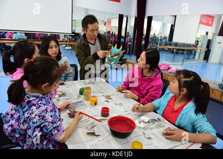 Enshi, Cina. 13 ottobre 2017. Gli studenti imparano a fare maschere dell'Opera Nuo a Enshi Tujia e nella prefettura autonoma di Miao nella provincia di Hubei della Cina centrale. Le maschere sono una caratteristica distintiva dell'Opera Nuo, un antico dramma popolare che è ancora popolare in molte province cinesi lungo il fiume Yangtze. Si ritiene che gli artisti della Nuo Opera acquisiscano la capacità di comunicare con le divinità una volta indossate le loro maschere. Crediti: ZUMA Press, Inc./Alamy Live News Foto Stock