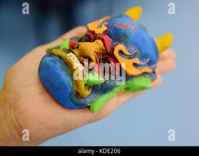 Enshi, Cina. 13 ottobre 2017. Gli studenti imparano a fare maschere dell'Opera Nuo a Enshi Tujia e nella prefettura autonoma di Miao nella provincia di Hubei della Cina centrale. Le maschere sono una caratteristica distintiva dell'Opera Nuo, un antico dramma popolare che è ancora popolare in molte province cinesi lungo il fiume Yangtze. Si ritiene che gli artisti della Nuo Opera acquisiscano la capacità di comunicare con le divinità una volta indossate le loro maschere. Crediti: ZUMA Press, Inc./Alamy Live News Foto Stock