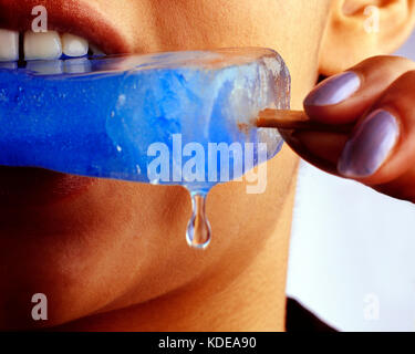 Giovane donna. In prossimità della bocca di mangiare blue ice per lecca-lecca. Foto Stock