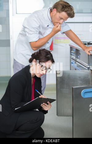 Lo chef cercando in questione come ispettore guarda in forno Foto Stock