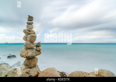 Un equilibrato mucchio di pietre di fronte alle onde dell'oceano. Foto Stock