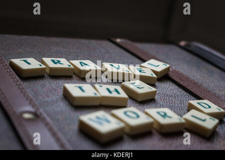 Viaggiare per il mondo a scrabble piastrelle valigetta in pelle di sfondo Foto Stock