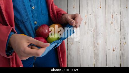 Composito Digitale della persona che detiene le mele in un ponticello contro il legno Foto Stock