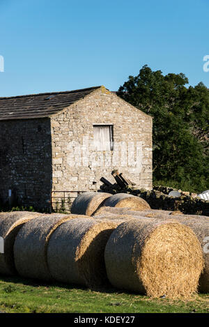 Il vecchio fienile e rotonde balle di fieno nel Yorkshire Dales, Inghilterra. Foto Stock