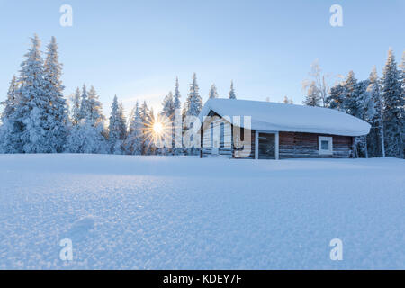 Sunburst sulla capanna in legno ricoperta di neve, Kiruna, norrbotten county, Lapponia, Svezia Foto Stock