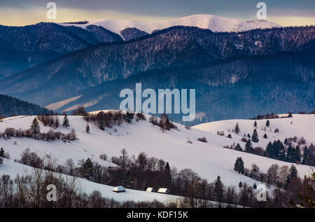 Stupendo paesaggio invernale in montagna sono rurali. bellissimo paesaggio di campagna con il villaggio e la foresta su strade coperte di neve colline di sunrise Foto Stock