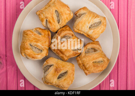 Pila o stack di selezione di salsiccia di maiale rotoli snack salati in pasticceria su una rosa di sfondo di legno Foto Stock