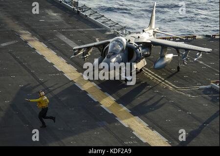 Un marinaio statunitense dirige un aereo d'attacco al suolo AV-8B Harrier II del corpo dei Marines che atterra sulla piattaforma di volo a bordo della nave d'assalto anfibia USS America della Marina americana il 16 luglio 2017 nell'Oceano Pacifico. (Foto di Ramon Go via Planetpix) Foto Stock