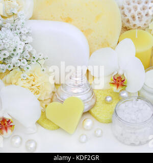 Il trattamento di bellezza pulizia e ex sfaldatura prodotti con orchidee e fiori di garofano, ex foliating sale, a forma di cuore sapone giallo e spugne. Foto Stock