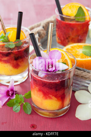 Un vivace cocktail con frutta fresca e colorata orchidee Foto Stock