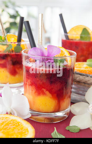 Un vivace cocktail con frutta fresca e colorata orchidee Foto Stock