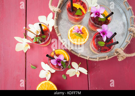 Un vivace cocktail con frutta fresca e colorata orchidee Foto Stock