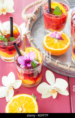 Un vivace cocktail con frutta fresca e colorata orchidee Foto Stock