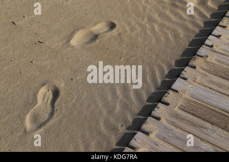 In prossimità di due impronte su di una spiaggia di sabbia a fianco di una passerella. Foto Stock