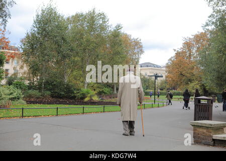 Il vecchio uomo asiatico con i capelli bianchi passeggiate a Regents Park, Londra, con un bastone Foto Stock