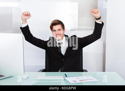 Felice successo giovane imprenditore entusiasta alzando la mano Foto Stock