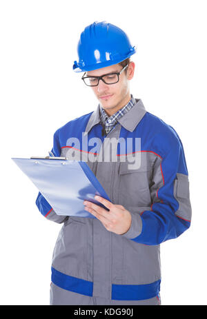 Costruzione di giovani recensore di indossare indumenti da lavoro e di compressori Hardhat iscritto negli appunti Foto Stock